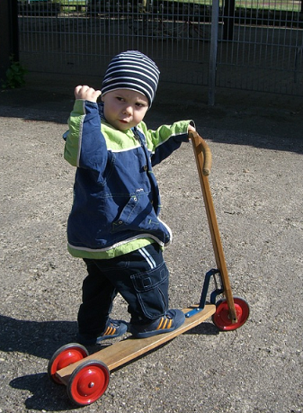 Boy clenching his fist while on a wooder scooter