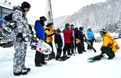 beginner snowboarders being taught by a senior snowboarder