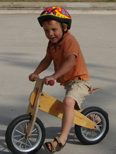 boy riding his wooden balance bike