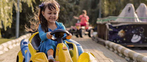 girl driving an electric car toy in safe track