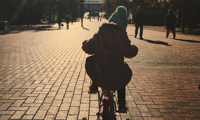 kid riding a 4-wheeled bicycle on the park