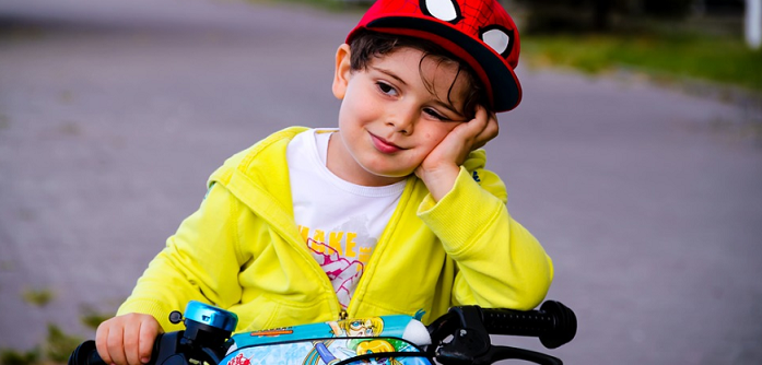 kid wearing yellow jacket smiling while riding a bike