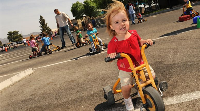 toddlers riding 3-wheeled bikes in the park